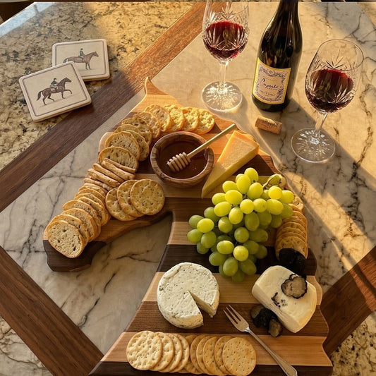 Horse head charcuterie board styled with assorted crackers, brie, grapes, and honey on granite surface