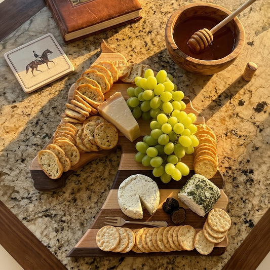 Handcrafted horse head charcuterie board with crackers, cheese, grapes, honey, and wine glasses on marble countertop